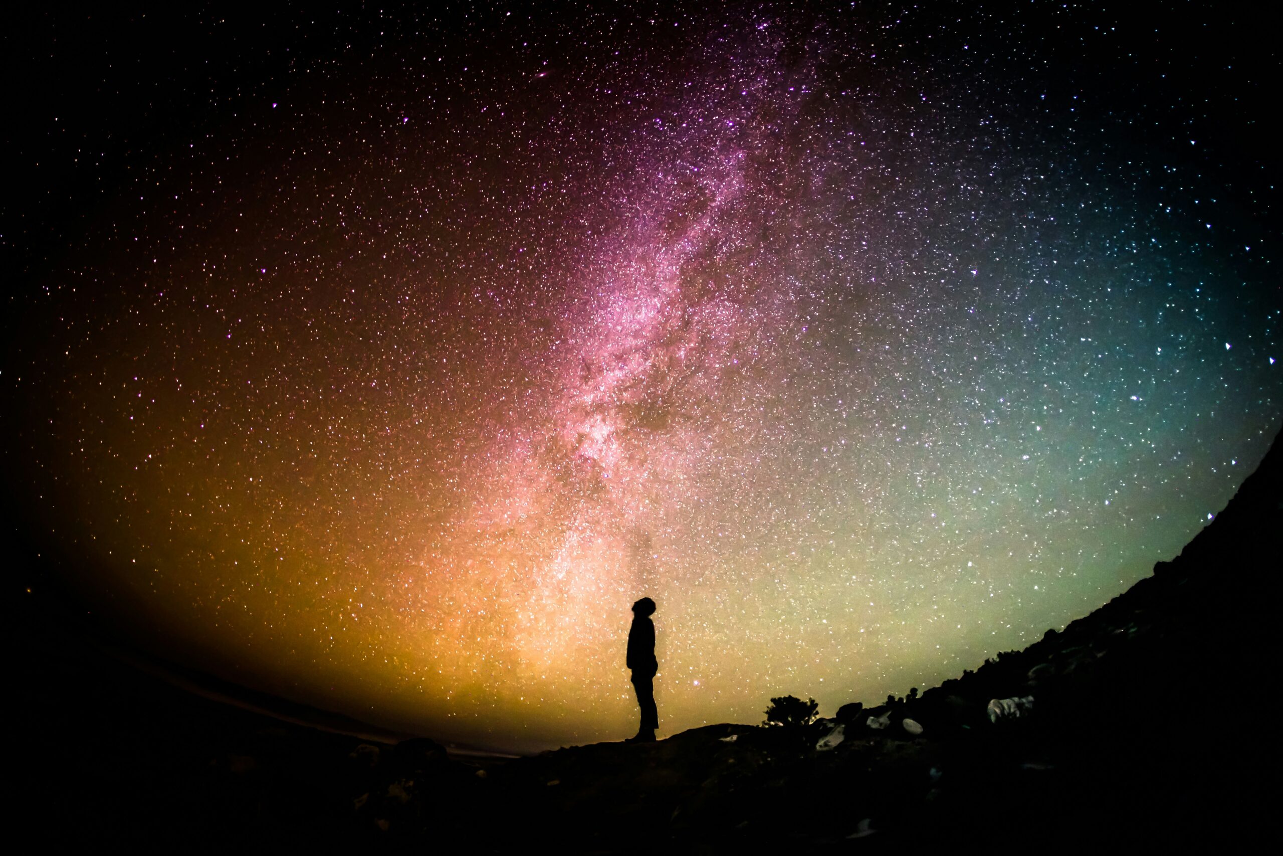 天の川を見上げる人物のシルエット。宇宙科学の研究が世界に与える大きさを表現した写真。