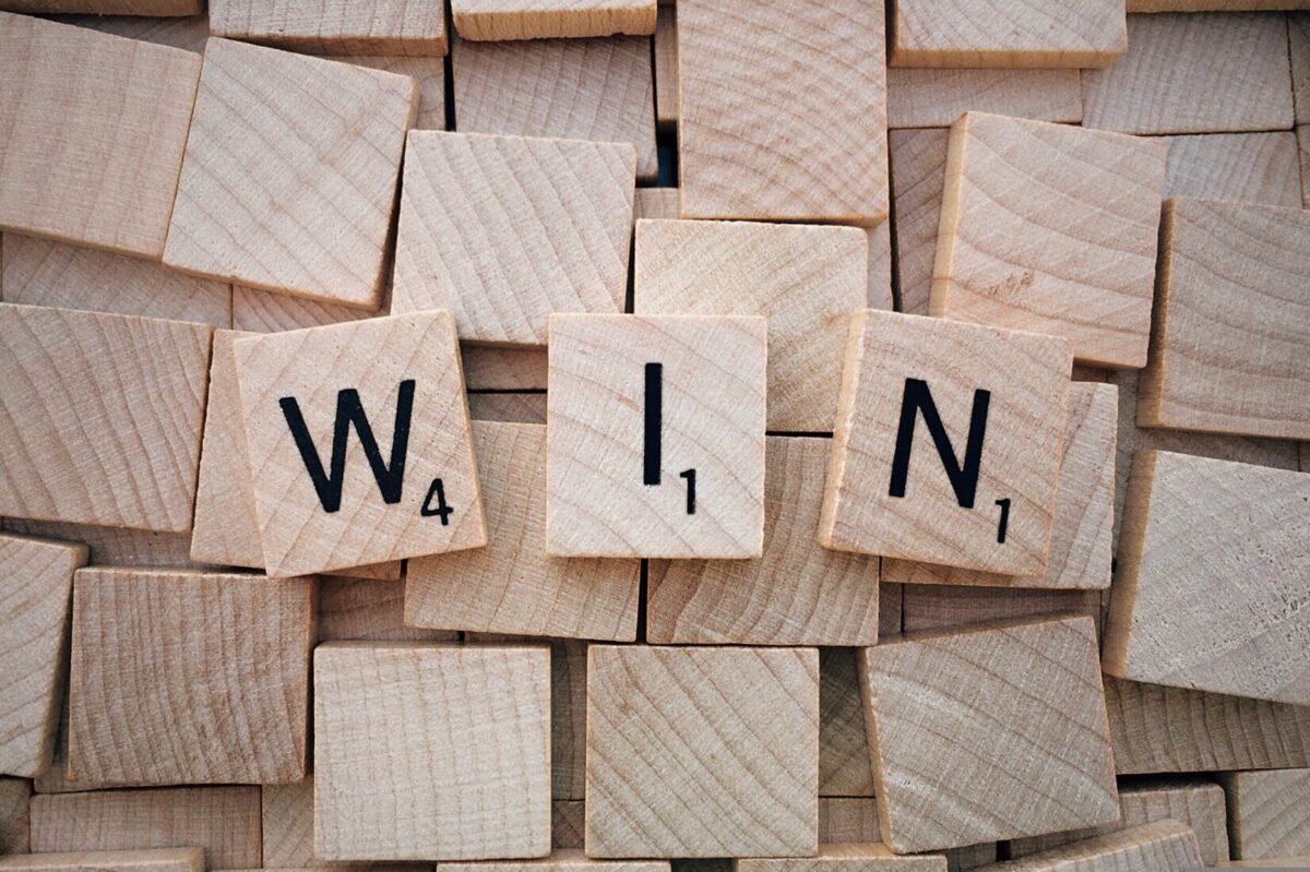 木製のスクラブルタイルで並べられた“WIN”の文字。達成や前進を象徴する写真。